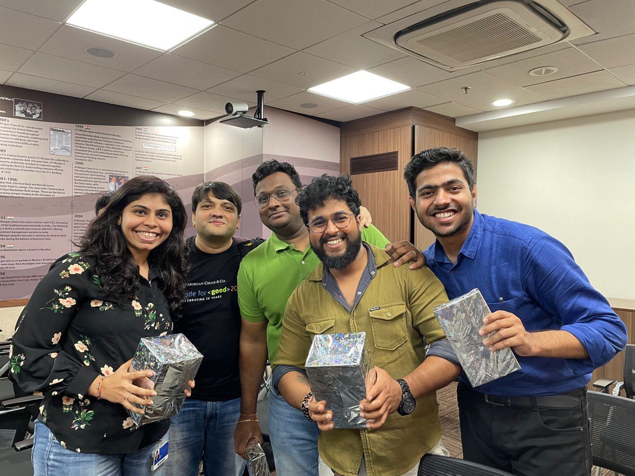 A picture with my team during internship, us holding gifts wrapped in silver gift paper.